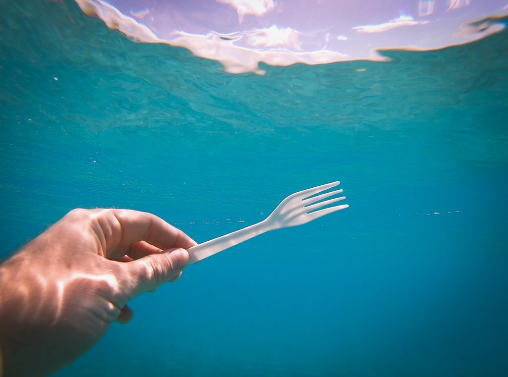 plastic fork trash next to blue water