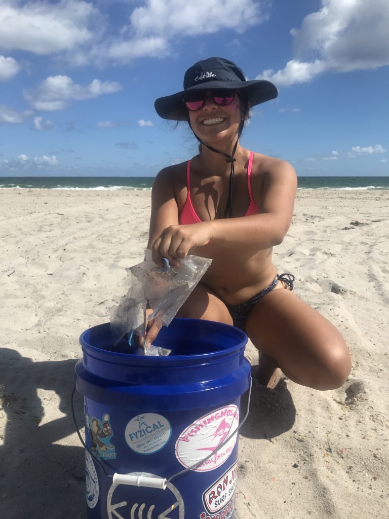 girl throwing away trash on the beach