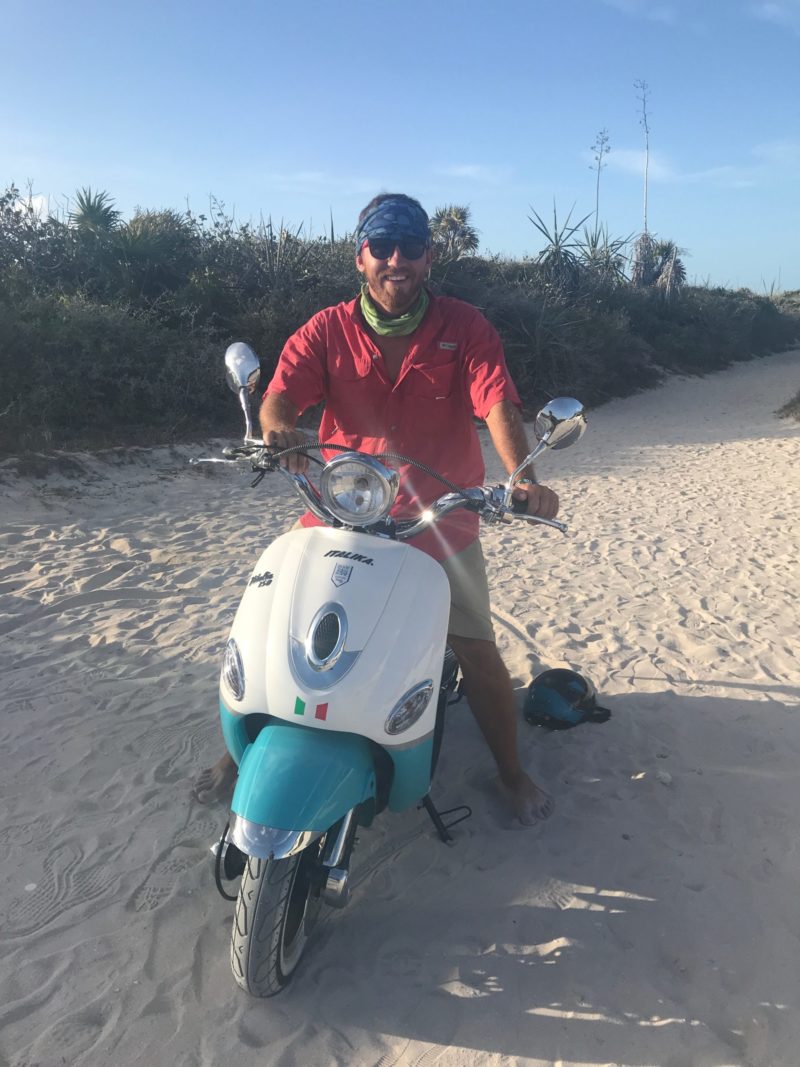 man on a moped in mexico on the beach