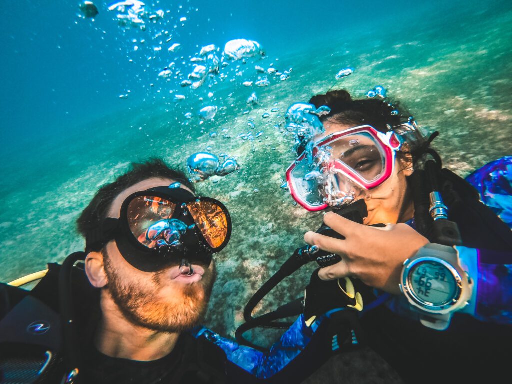 man and woman scuba diver blowing bubbles