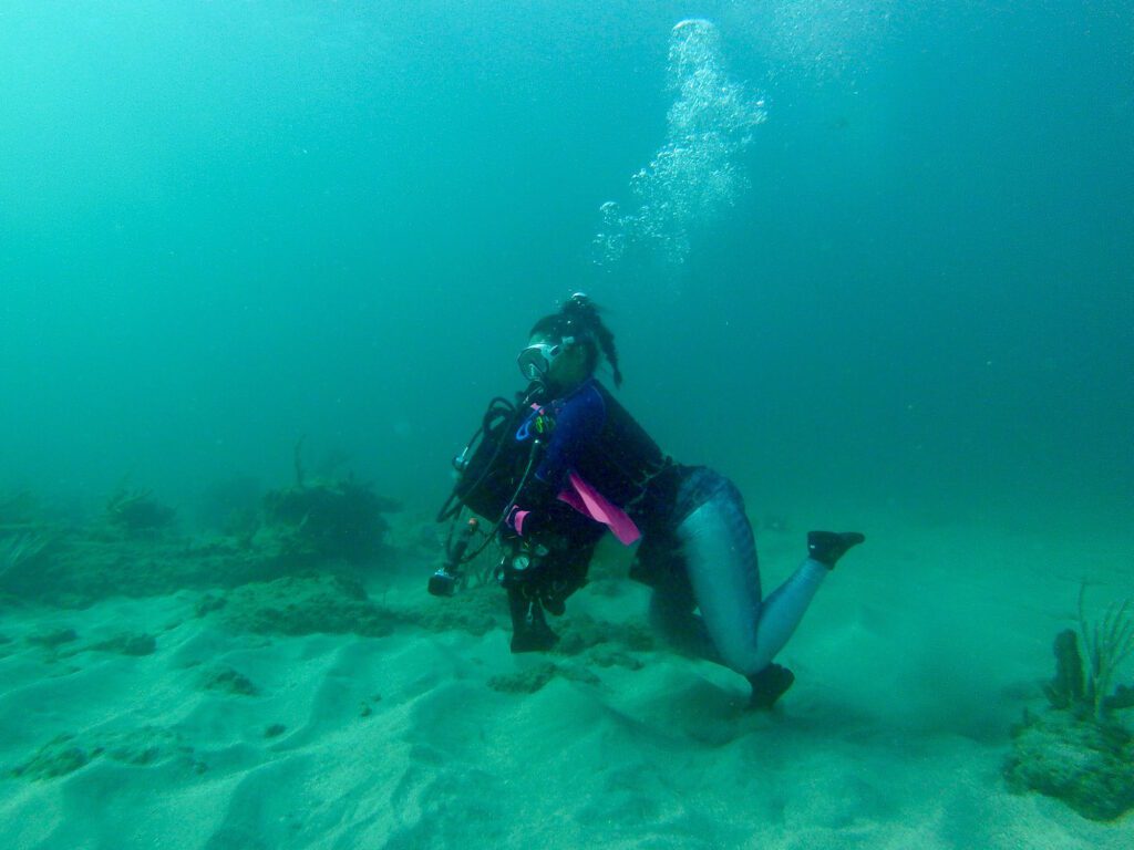 woman carrying dive gear underwater