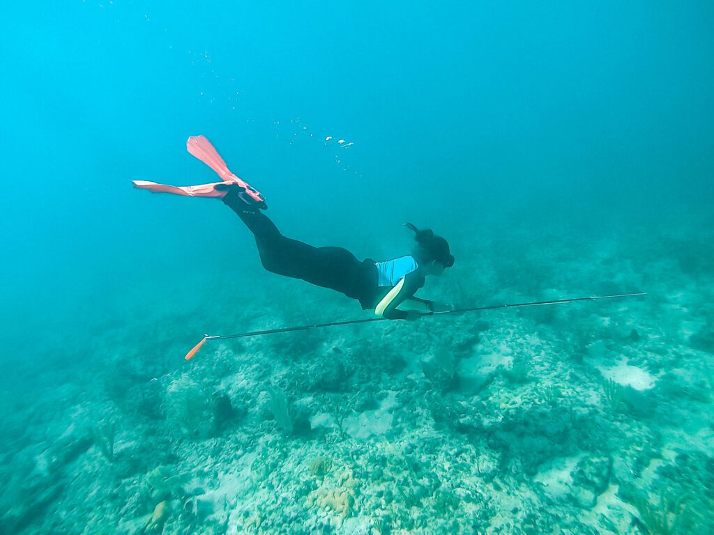 woman freediving with a spear and pink fins to hunt