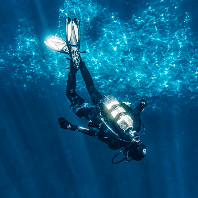 scuba diver descending into blue