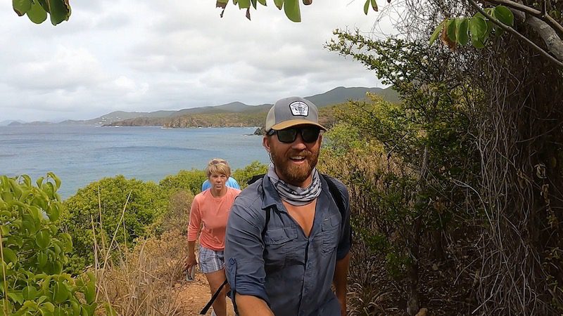 man and woman hiking up ram head trail with st john usvi in the background