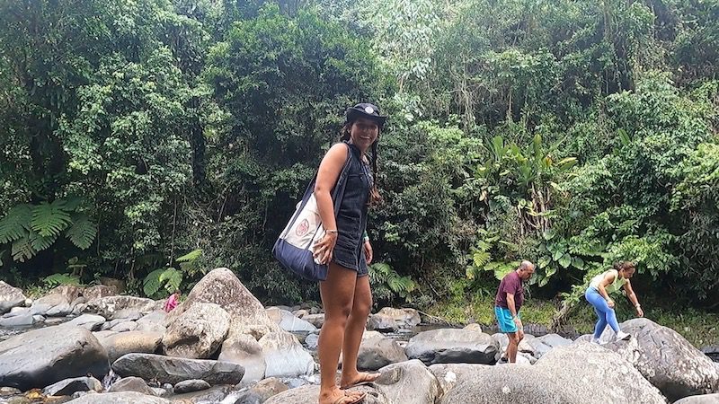 woman smiling atop rocks in el yunque national forest