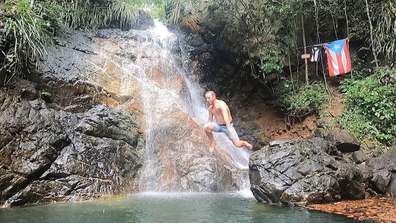 man jumping into natural swimming pool waterfall hiking trail san german
